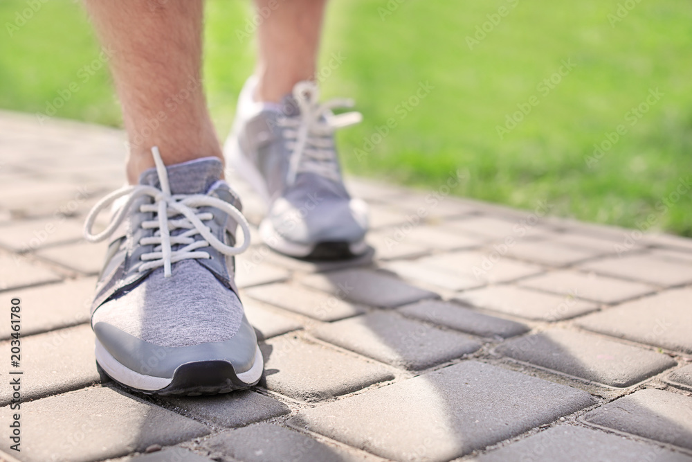 Sporty young man in training shoes outdoors, closeup