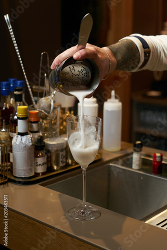 Professional bartender making a cocktail at the bar counter, close-up