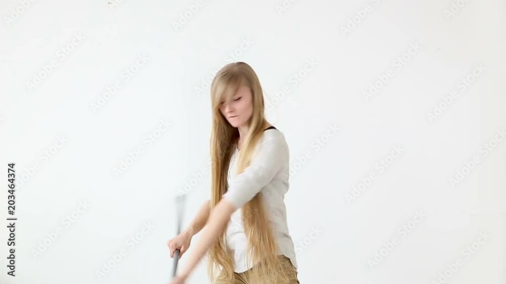 Cheerful attractive teen girl sings and dances with a broom like a microphone over white background. Cheerful attractive teen girl sings and dances with a broom like a microphone over white background.