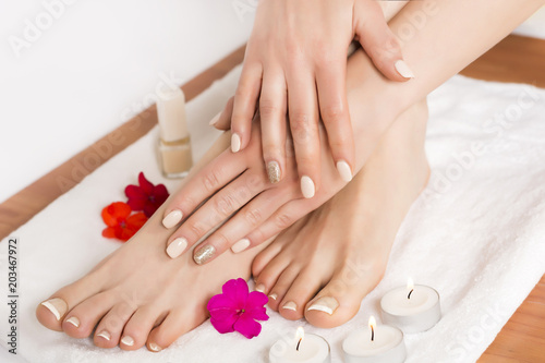 Beauty female feet and hands at spa salon on pedicure procedure and flowers and candles on white towel. Close up  selective focus