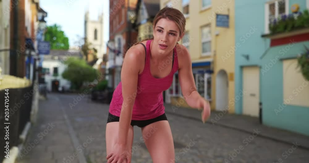 Pretty white female runner taking break from running in European neighborhood