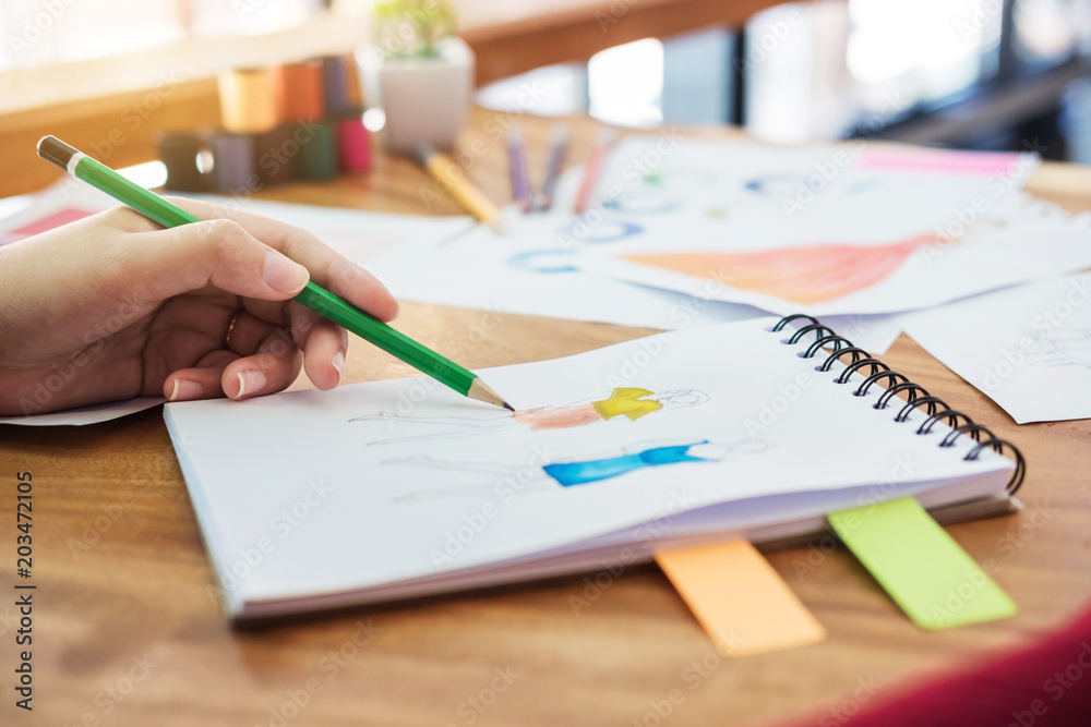 Close up of professional Fashion designer working and drawing sketches for clothes in workplace and color charts Close up of professional Fashion designer working and drawing sketches for clothes in workplace and color charts
