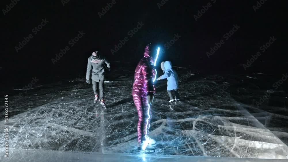 Family is ice skating night. Girls and boys to ride figure ice skates in nature. Mother daughter and son riding together on ice in cracks. Outdoor winter fun for athlete nice winter weather. People on Family is ice skating night. Girls and boys to ride figure ice skates in nature. Mother daughter and son riding together on ice in cracks. Outdoor winter fun for athlete nice winter weather. People on