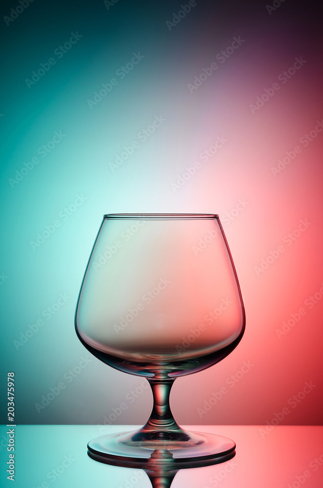 Empty glass for cognac on color, gradient background.