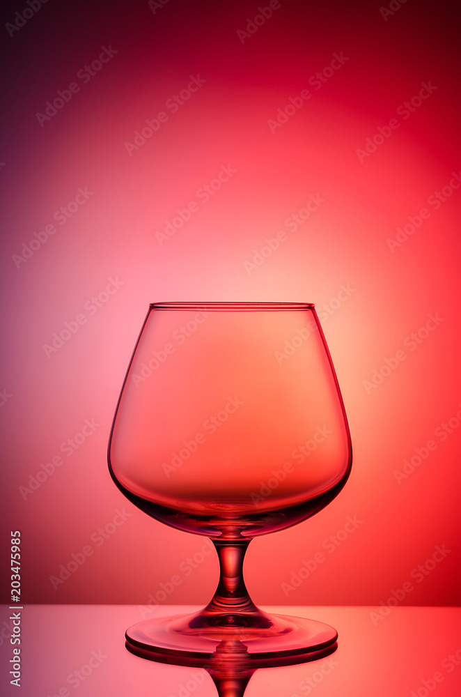 Empty glass for cognac on color, gradient background.