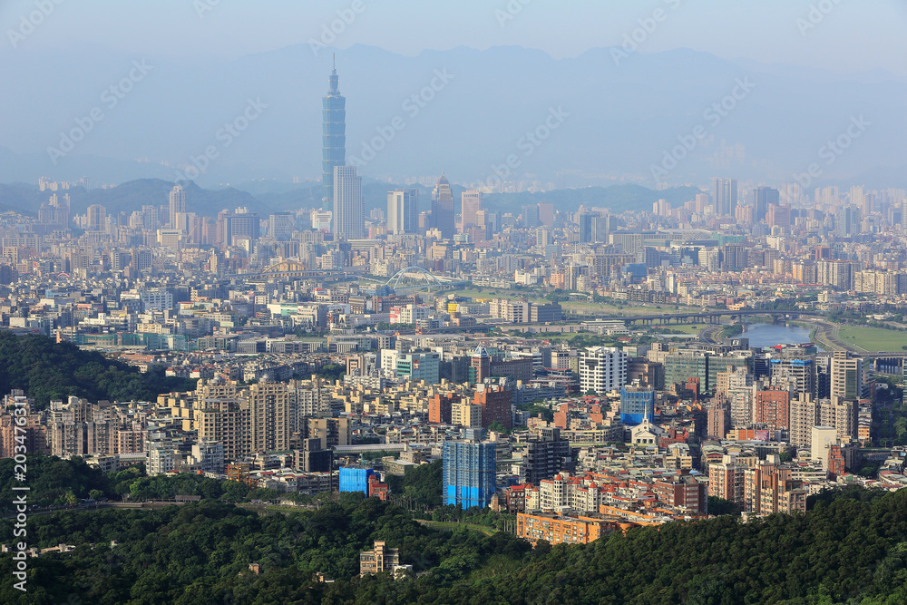Aerial panoramic scene of overpopulated Taipei City in a hazy morning with a view of Taipei 101 tower in XinYi District, and Keelung River through the downtown area