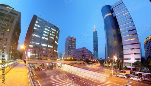 Panoramic view of a street corner in Downtown Taipei City with busy traffic trails at rush hour   Beautiful night scenery of Taipei 101 Tower    landmark buildings in XinYi Financial District