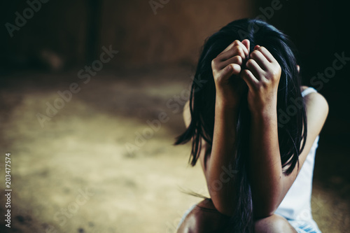 Little sad girl hiding or locked in the basement. trafficked and abused photo