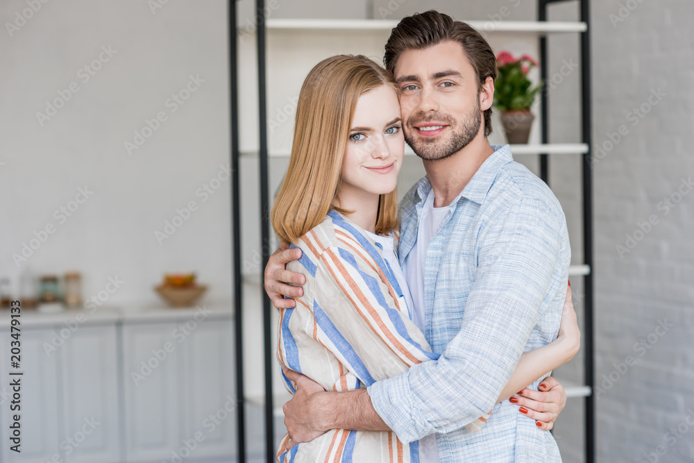 young couple hugging each other and looking at camera