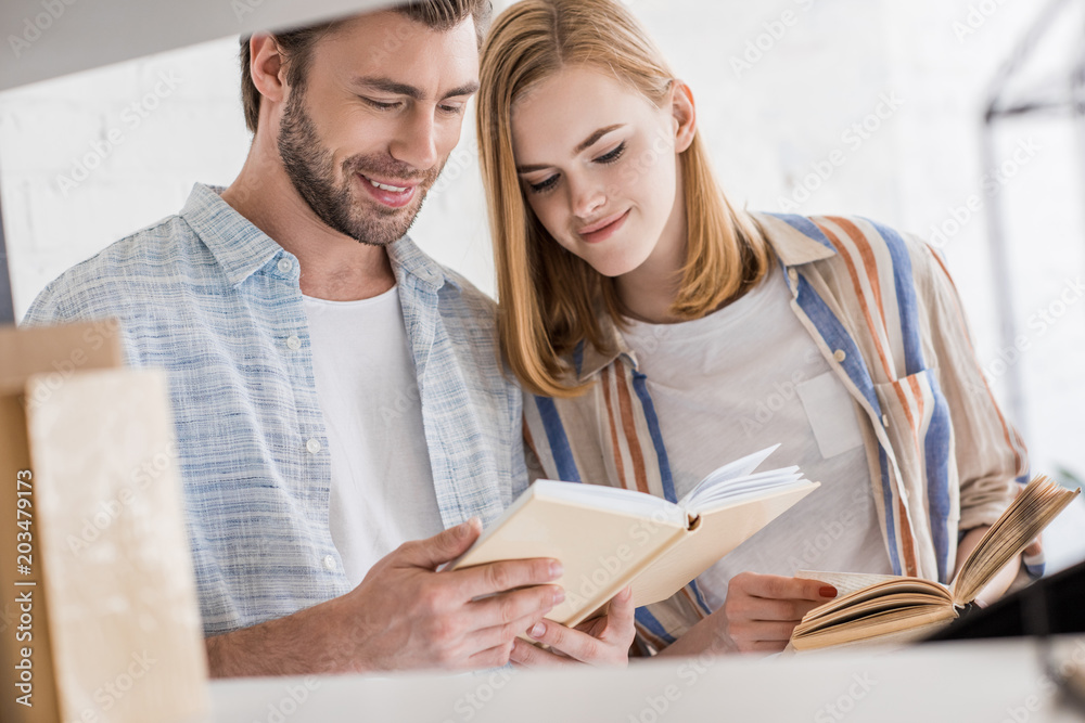 smiling young woman looking at boyfriend book smiling young woman looking at boyfriend book