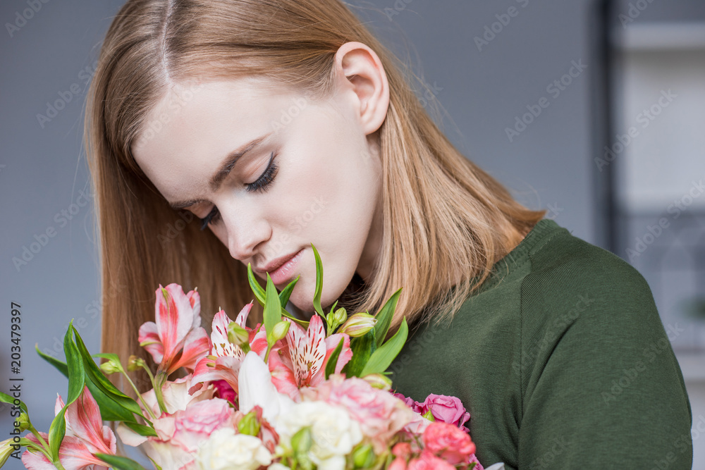 attractive young woman sniffing bouquet of flowers attractive young woman sniffing bouquet of flowers