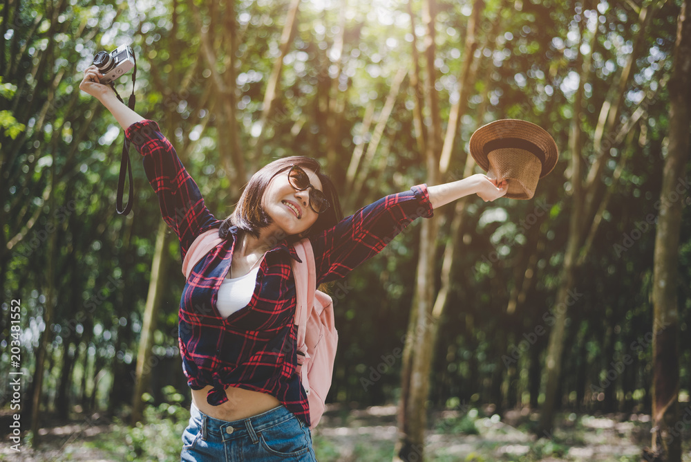 Happiness Asian traveler woman in forest with spread arms and enjoy fresh air. Relax time and Adventure concept. Vacation and Holiday concept. Woods and countryside background theme.