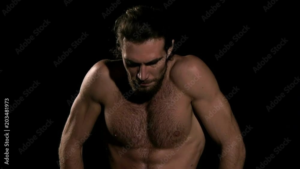 Very fit man doing warm up before exercise with black background. Sitting down and relaxing. Slow motion. Very fit man doing warm up before exercise with black background. Sitting down and relaxing. Slow motion.