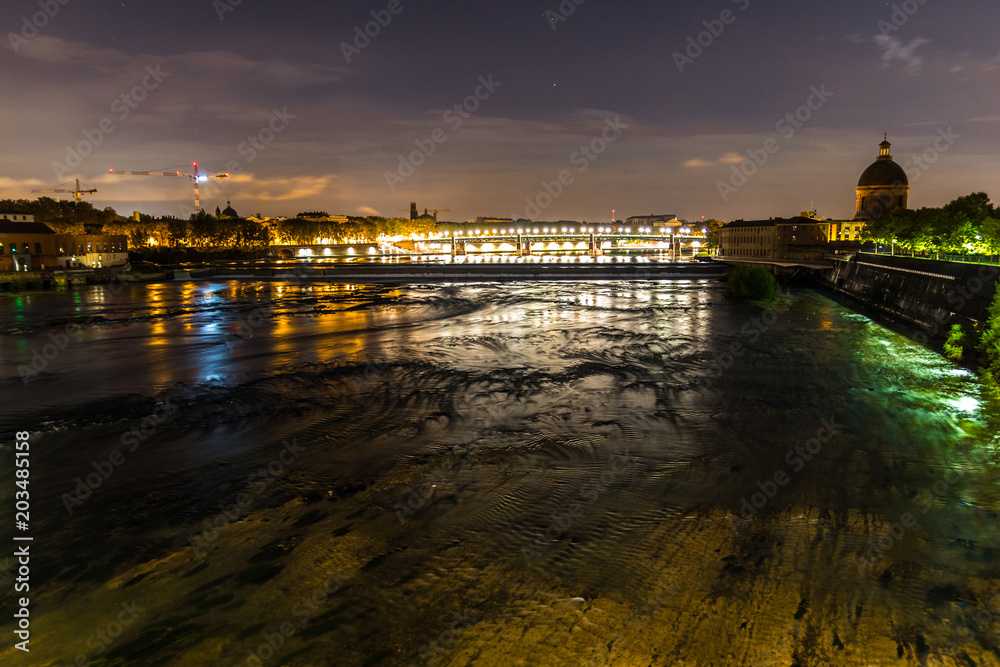 Night view of Toulouse, France, and the Garonne river, with the St Pierre bridge and the la Grave dome in the background.