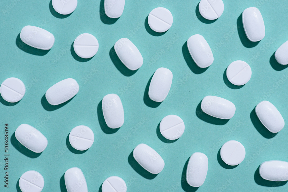 top view of white pills on blue surface top view of white pills on blue surface