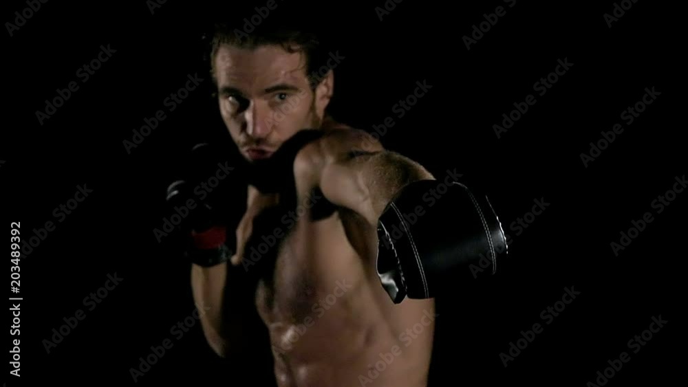 Slow motion of man shadow boxing in black background. Young white man with six packs.. Fighting sprit concept. Slow motion of man shadow boxing in black background. Young white man with six packs.. Fighting sprit concept.