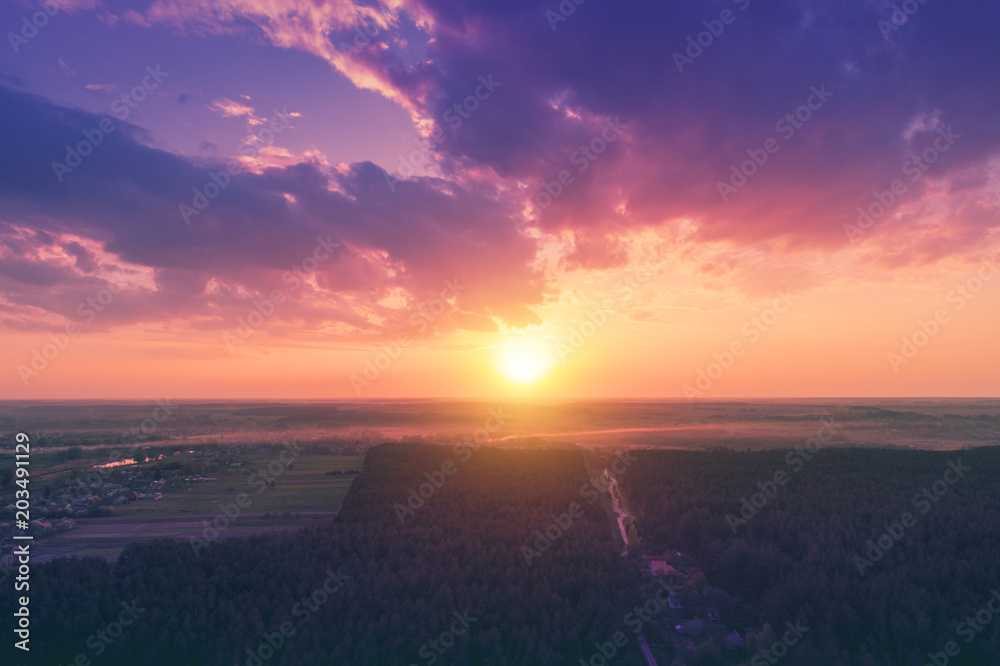Aerial drone view of countryside, rural landscape with cloudy sky at sunset