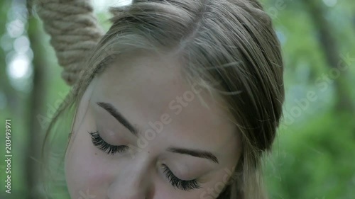 A woman's head in a loop hung in the woods