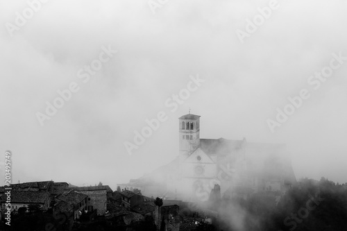View of St. Francis papal church in Assisi (Umbria, Italy) in the middle of lifting morning fog