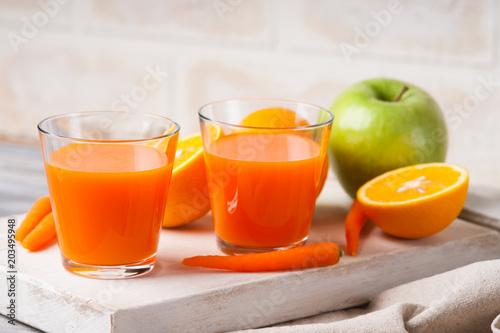 Glasses with carrot juice, apple, mint leaf and sliced orange 