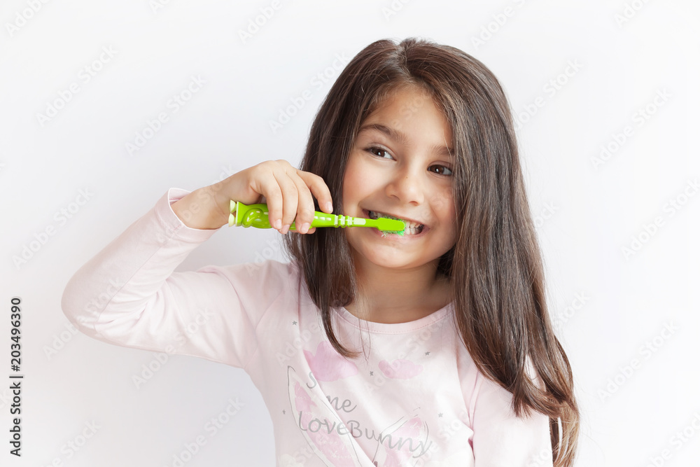 Little cute child girl brushing her teeth on white background. Space for text. Healthy teeth. Little cute child girl brushing her teeth on white background. Space for text. Healthy teeth.