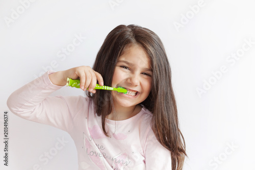 Little cute child girl brushing her teeth on white background. Space for text. Healthy teeth.