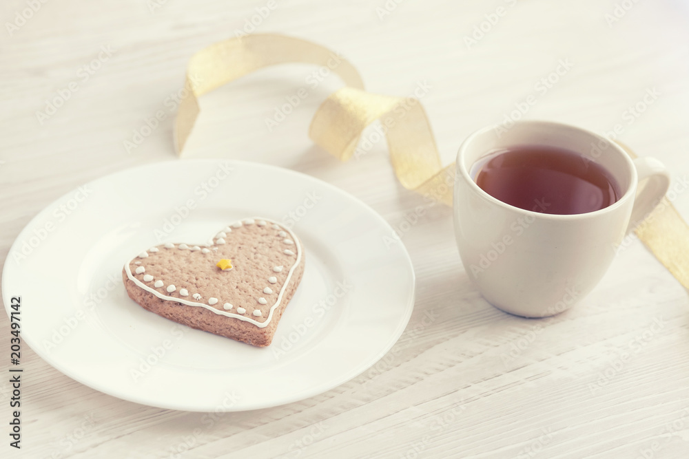 Love consept. Valentines day. Gingerbread in the shape of heart, a cup of tea, decorative hearts on a wooden table Love consept. Valentines day. Gingerbread in the shape of heart, a cup of tea, decorative hearts on a wooden table
