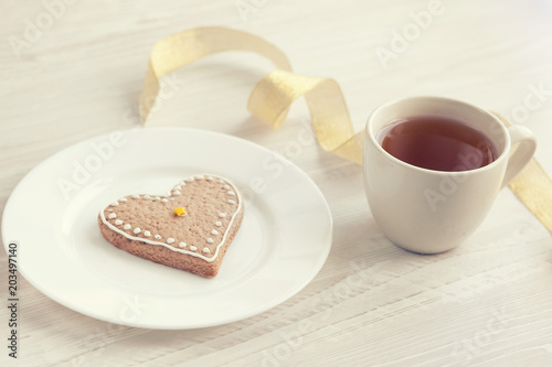 Love consept.  Valentines day. Gingerbread in the shape of heart, a cup of tea, decorative hearts on a wooden table 