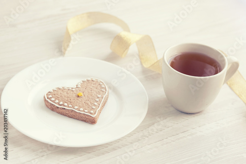 Love consept.  Valentines day. Gingerbread in the shape of heart, a cup of tea, decorative hearts on a wooden table 