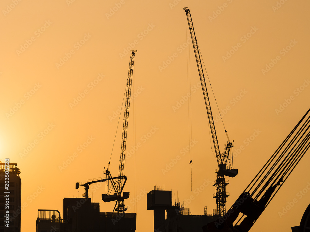 Cranes working on Building Construction site sunset sky Silhouette Industrial background Cranes working on Building Construction site sunset sky Silhouette Industrial background