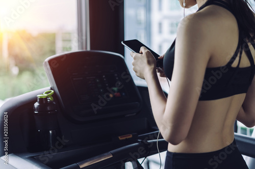 Woman cardio running workout listening music using earphones holding smartphone
