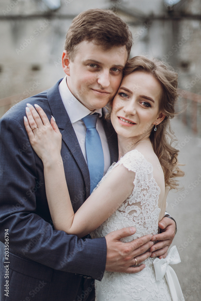 Happy couple of newlyweds posing near castle, fairytale wedding moment beautiful bride and groom hug near ancient castle entrance in Europe