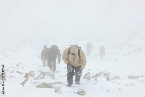 Climb to the top of mountain in extreme weather conditions photo