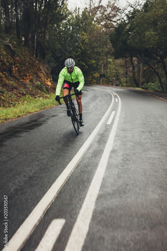 Bicycle rider with bike on wet asphalt road © Jacob Lund