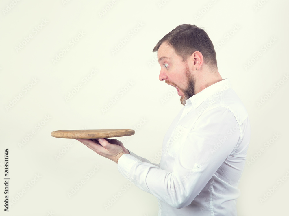 Adult business man looks at the wooden tray in his hands with surprise. Place for text. Adult business man looks at the wooden tray in his hands with surprise. Place for text.