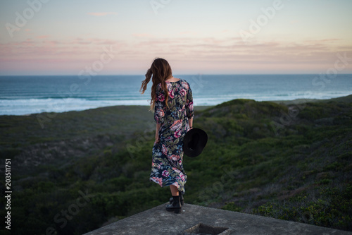 Girl in flower dress overlooks the ocean