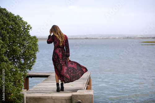 Obraz na plátne Women walks on jetty overlooking the river