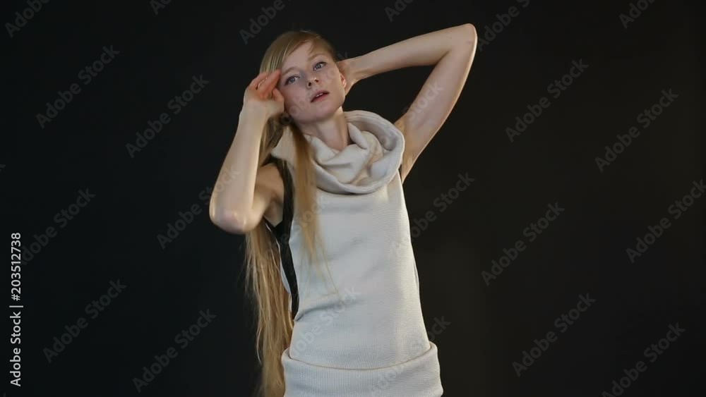 blonde model of European appearance posing in front of camera in studio on black background blonde model of European appearance posing in front of camera in studio on black background