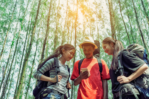 Teenager group friends with backpack and guitar looking smartphone have phone navigation to enjoy adventure,Travel and Recreation Concept