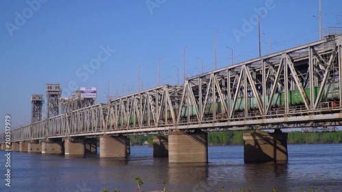 The train travels across the bridge over the river photo