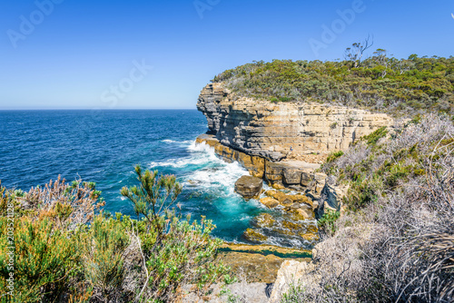 Fototapeta Naklejka Na Ścianę i Meble -  Tasman Peninsula, Tasmania, Australia: Scenic coastline of rocky cliff Tasman arch with old stone formations dramatic structures near blue wild ocean perfect hiking landscape countryside Port Arthur