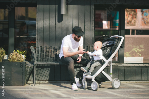 Father walking with a stroller and a baby in the city streets