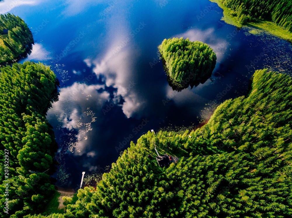 Aerial view of blue lake with island and green forests on a sunny summer day in Finland. Aerial view of blue lake with island and green forests on a sunny summer day in Finland.