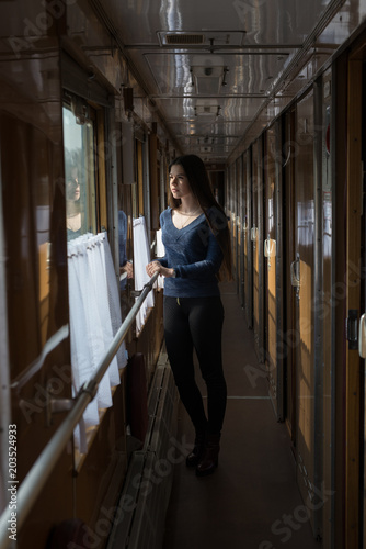 A young girl stands in a train car and looks out the window