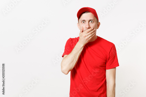 Delivery man in red uniform isolated on white background. Professional serious shocked male in cap, t-shirt working as courier or dealer, cover mouth with hand gesture. Copy space for advertisement.