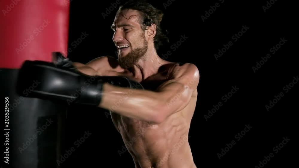 Slow motion of boxer punch a punching bag. Young white man with beard in black background. Fighting sport fitness concept. Slow motion of boxer punch a punching bag. Young white man with beard in black background. Fighting sport fitness concept.