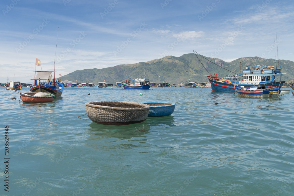 fishing boats, junks in the sea bay near the island of Vinperl, amidst the islands covered with tropical vegetation and blue sky, Vietnam