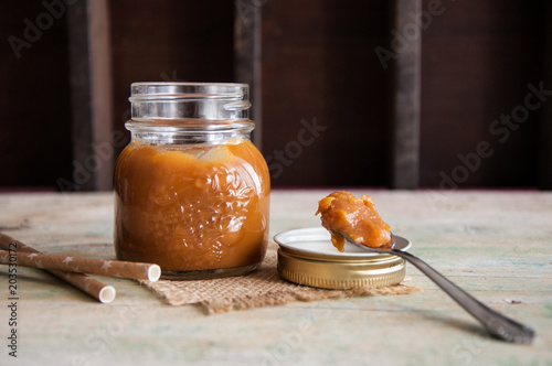 Homemade salted caramel in jar on wooden background