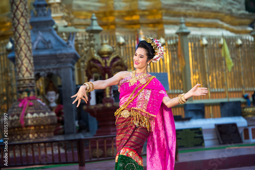 portrait of a young beautiful Thai dancer dancing in front of the pagoda of Wat Prathat Hariphunchai  Lampoon  Thailand