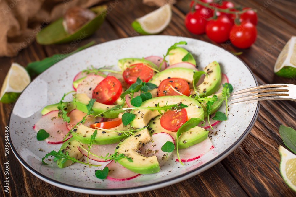 Vegetable salad with avocado, arugula, radish, lime and olive oil. Dietary healthy food. Wooden rustic background. Top view Vegetable salad with avocado, arugula, radish, lime and olive oil. Dietary healthy food. Wooden rustic background. Top view